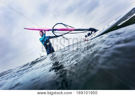 surfer standing in the water, waiting for the wind and waves before he steps up his surfboard