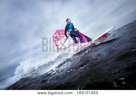A windsurfer tilts the rig and carves the board to perform a planing or jibe