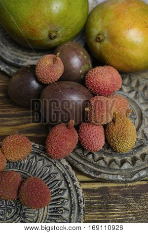 Tropical fruits - Lychees and Passion Fruit or Maracuya and Mango on wooden background