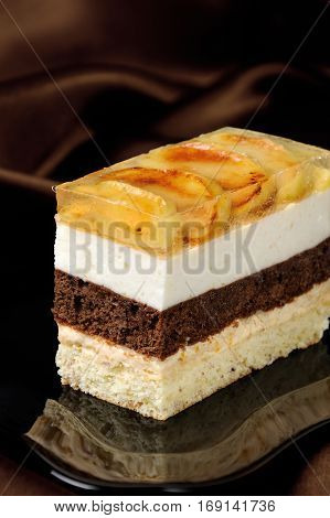 Cake stacked from caramel apple mousse chocolate and almond biscuit with a jelly layer of slices caramelized apple