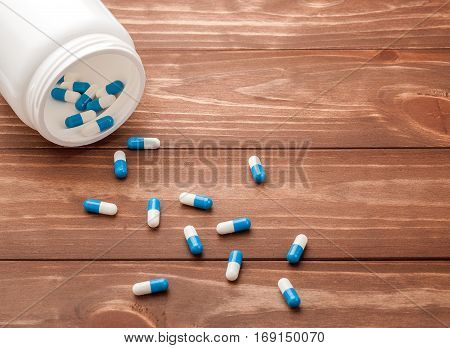 pills in a white jar on a wooden background