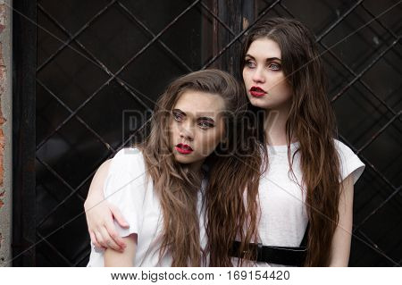Two scared frightened horror girl in white dressing gown looking aside. Theme Halloween. Dark picture of two beautiful scared hiding girls with opened mouth on black window background.