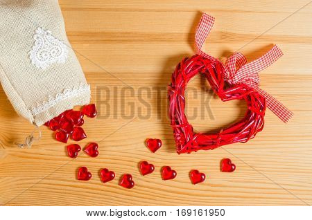 Heart on a wooden texture, and spilling out of the bag with small glass hearts