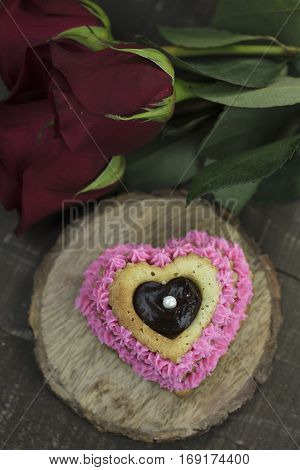 Heart shaped cupcake with pink icing and ganache filling garnished with red roses.