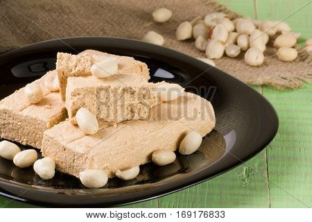 peanut halva in the plate on a green wooden background.