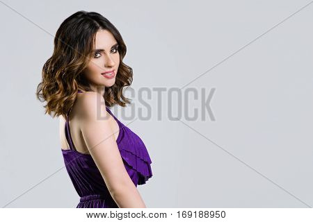 Portrait of beautiful woman in purple dress on a light background