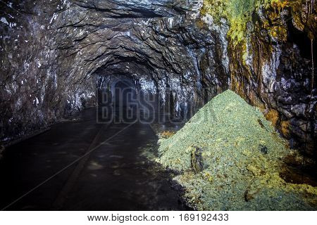 Flooded tunnel of an old abandoned coal mine with rusty remnants of railroad