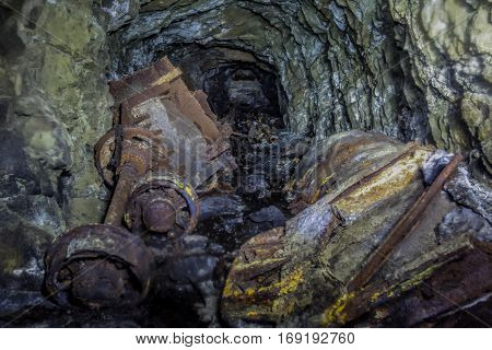 Collapse in tunnel of abandoned mine with rusty remnants of trolleys