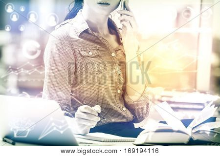 Attractive caucasian woman at workpace with abstract business charts talking on the phone and working on project. Accounting concept. Toned image