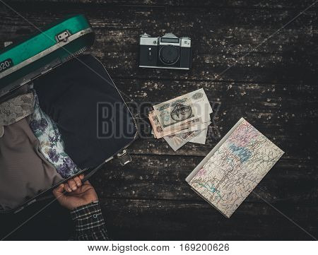 Vintage hipster suitcase packing before travel with old suitcase camera and accessories on a wooden table top view