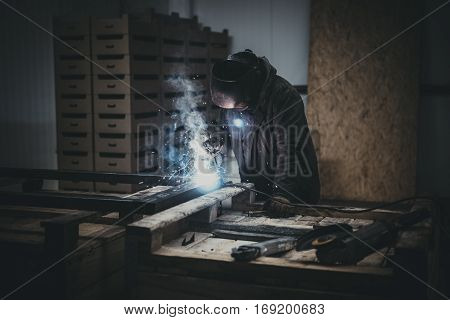 Welder working a welding metal with protective mask and sparks