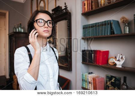 Authoress in glasses and white shirt talking on phone and looking away