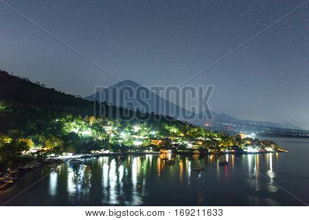 Jemeluk Beach and beautiful Agung volcano with a stars sky at night, Amed village, East of Bali, Indonesia.