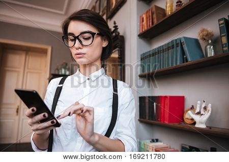 Authoress in glasses and white shirt writing message on phone