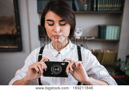 Attractive Authoress in white shirt making photo on retro camera