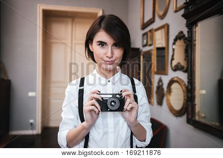 Beauty Authoress in white shirt making photo on retro camera and looking at camera