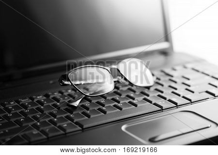 Black laptop and glasses close up image
