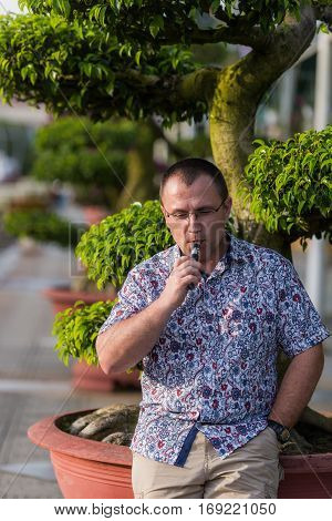 Adult senior man vaping electronic cigarette outdoor.