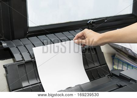woman hand putting a sheet of paper into a copying device