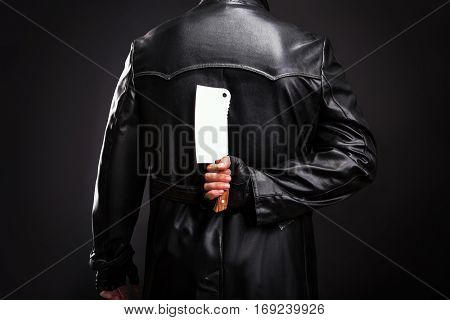 Serial murderer holding meat cleaver behind back