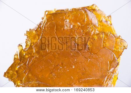 Big piece of cannabis oil concentrate aka shatter isolated over white background