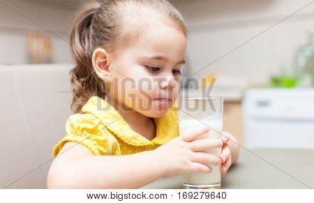 Child girl drinking milk at the kitchen