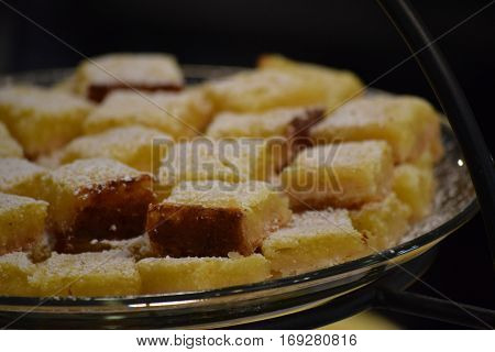 Lemon squares covered with powdered sugar on a serving tray.