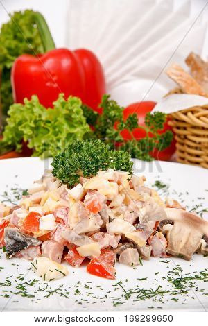 Ham salad with mushrooms on a white plate with fresh herbs
