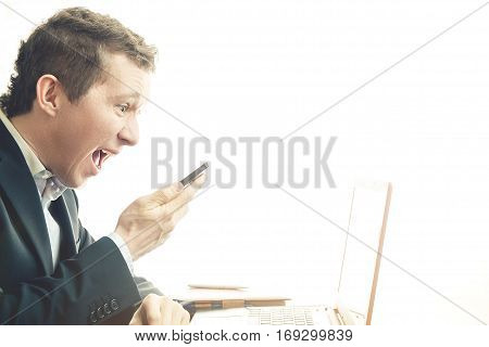Angry business man working at office. He yells at phone