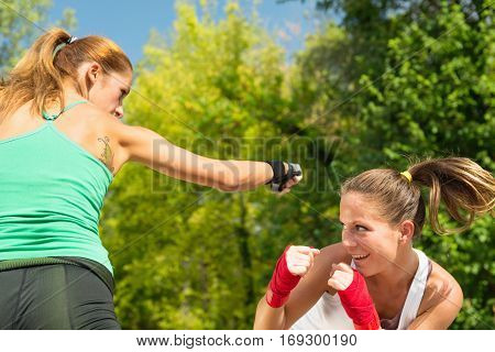 Two girls TaeBo boxing, toned image, outdoors