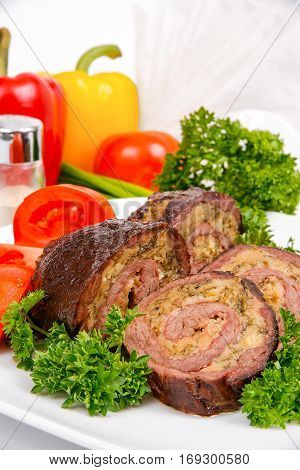 Meatloaf with tomato and herbs on a white plate