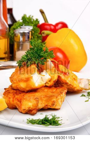Fish burgers with vegetables on the white plate with greens