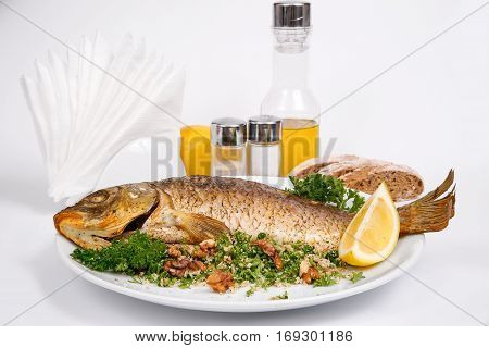 Carp stuffed with vegetables and raisins with greens and walnuts on a white plate