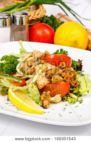 Salmon salad and mussels on a white plate with vegetables