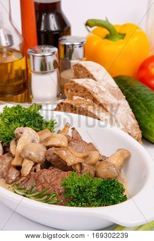 Fricassee of veal brisket with mushrooms on a white plate with fresh herbs