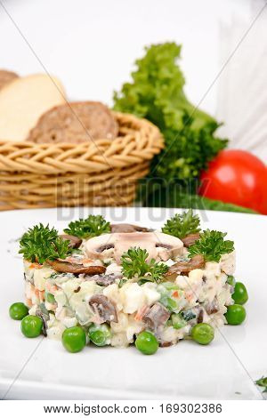 Olivier salad with mushrooms on a white plate