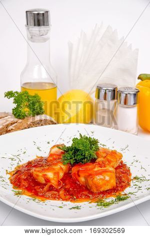 Fish in tomato sauce with parsley on a white plate