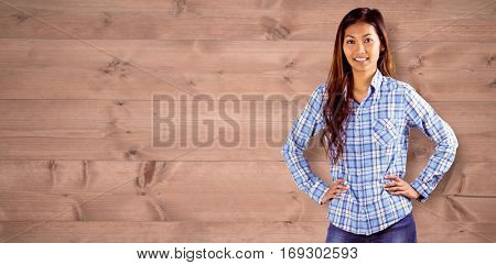 Smiling asian woman with hands on hips against bleached wooden planks background