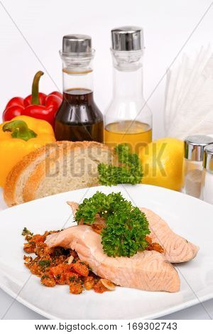 Salmon in nut-tomato sauce with herbs and spices on a white plate