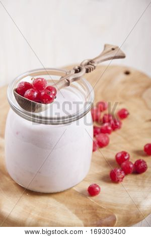 Smoothies with frozen red currants in jar on a wooden stand.