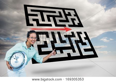 Delighted businesswoman holding a clock against maze with arrow in sky