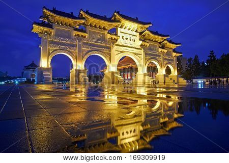 Asia culture - night view of Liberty Square (Archway of Chiang Kai Shek Memorial Hall) with reflection in raining day Taipei Taiwan. the Chinese text on the archway : Liberty Square