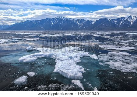 Big ice floe with blue underwater foundation, spring landscape