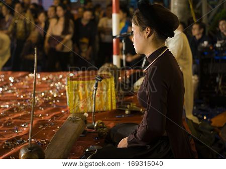 Hanoi, Vietnam - Nov 2, 2014: Side portrait of Vietnamese artist perform folk music and song on Ma May st, old town of Hanoi. The show is free for tourist every night