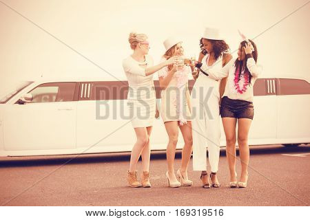 Frivolous women drinking champagne next limousine for night out
