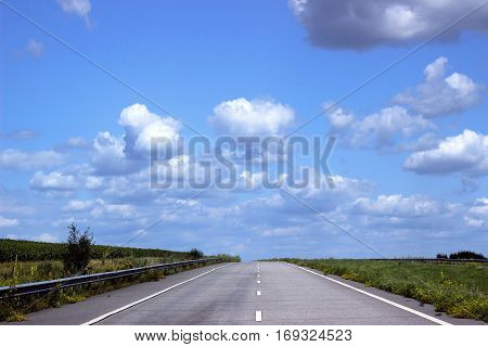 Paved road on the background of blue sky leaving for horizon.