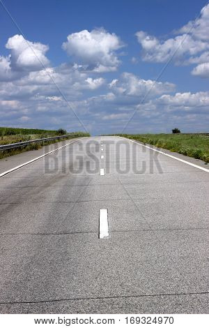 Paved road on the background of blue sky leaving for horizon.