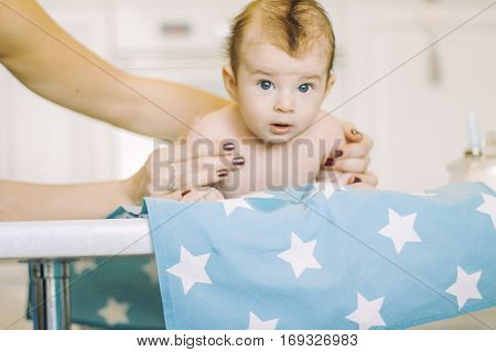 small child learns to help parents keep his head. baby lying on a blue diaper in a star. parental support.