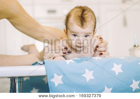 small child learns to help parents keep his head. baby lying on a blue diaper in a star. parental support.