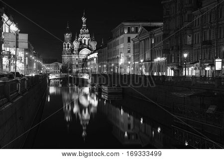 Illuminated Church on Spilled Blood with dark sky in Saint Petersburg Russia. Griboyedov canal and busy street with many cafes restaurants and shops. Black and white